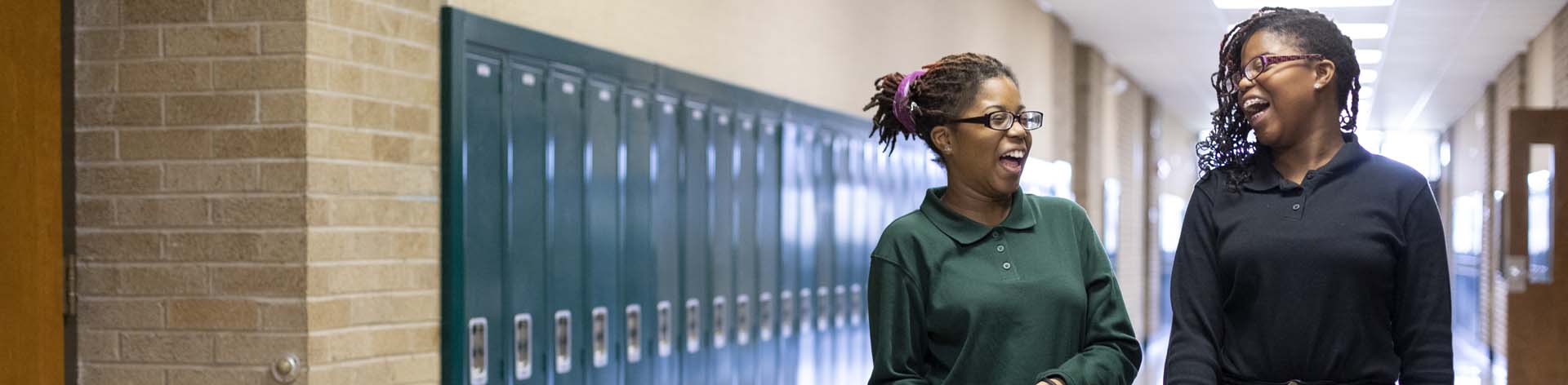 Two blind teenage sisters smile together and chat outside of class.